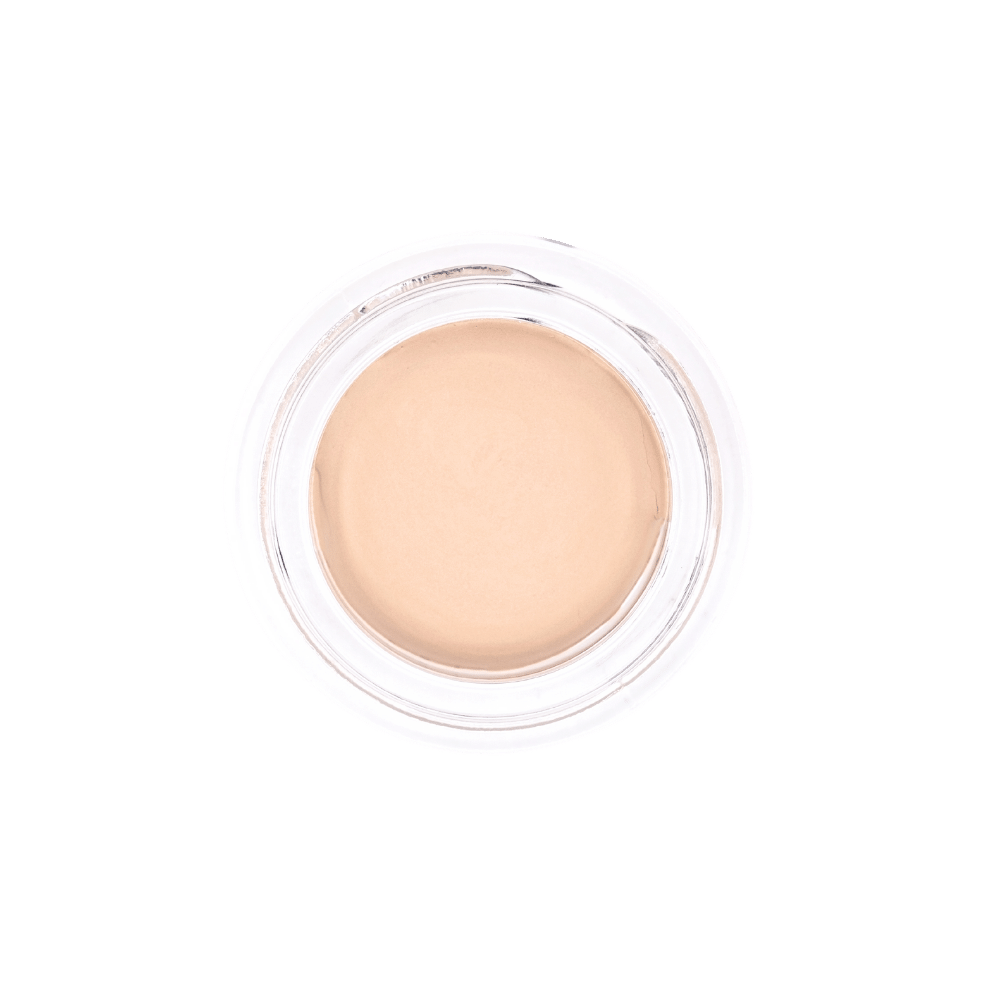Straight-down view of 'Nude Beach' All-Over Brightening Concealer by Dr. Berrettini's Mendocino Minerals, light to light-medium shade with peach undertones, in a glass bottom.