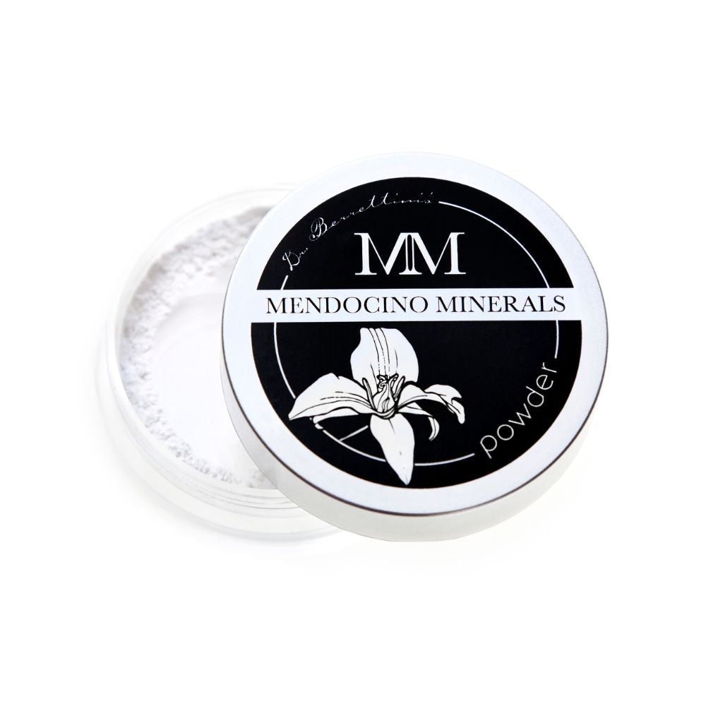 Slightly angled top view of Dr. Berrettini's Mendocino Minerals Serum-Infused, Soft Focus HD Powder. The container, with a clear bottom and matte silver top, contains white powder. The lid is partially removed, revealing the powder inside.